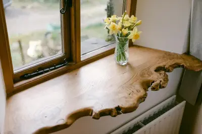 a vase of flowers on a window sill with a vase of flowers at Crookabeck B&B in Patterdale