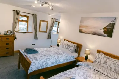 a bedroom with two beds and two windows at Crookabeck B&B in Patterdale