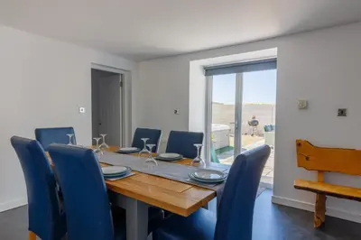a dining room with a wooden table and blue chairs at The Stables at Brickrow Farm in Ayr