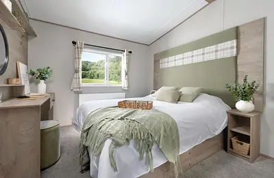 a bedroom with a large bed and a window at Queensberry Bay Essential Clover Caravan in Annan