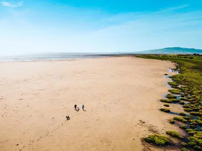 two people walking on a beach near the ocean at Queensberry Bay Essential Clover Caravan in Annan