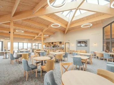 a dining room with tables and chairs and windows at Queensberry Bay Essential Clover Caravan in Annan