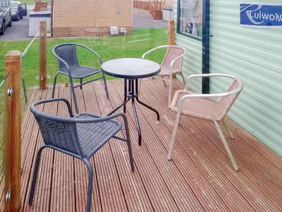 three chairs and a table on a deck at Regal Lodge in Plumbland