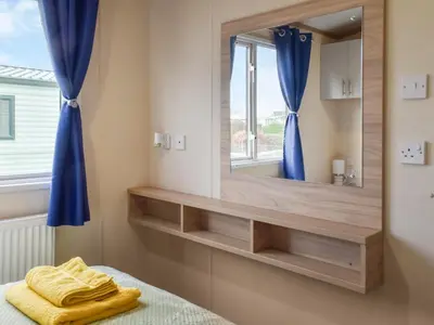 a bathroom with a large mirror and a bed at Regal Lodge in Plumbland