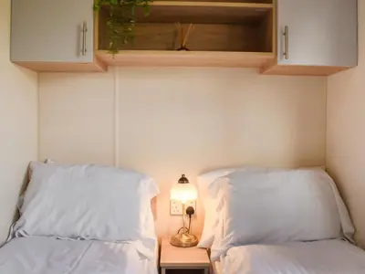 two beds with white pillows and a table with a lamp at Regal Lodge in Plumbland