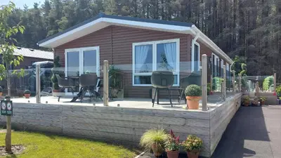 a house with a deck with chairs and windows at Antler Lodge - Meadows Retreat Lodge Park in Plumbland