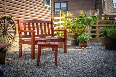 a wooden bench and a chair in a yard at Antler Lodge - Meadows Retreat Lodge Park in Plumbland