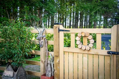a wooden fence with a door with a bunch of logs at Antler Lodge - Meadows Retreat Lodge Park in Plumbland