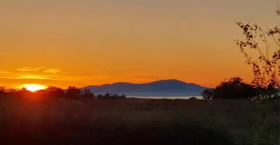 a sunset over a field with a mountain in the background at Antler Lodge - Meadows Retreat Lodge Park in Plumbland