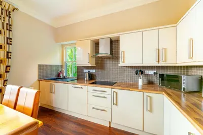 a kitchen with white cabinets and a wooden table at Langdale Crag in Grasmere