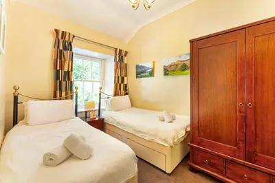 a bedroom with two beds and a wooden cabinet at Langdale Crag in Grasmere