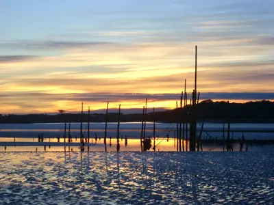 a sunset over a body of water with poles in the snow at The Shack, Cally Avenue, Gatehouse of Fleet, Dumfries and Galloway, DG7 2 DH in Gatehouse of Fleet