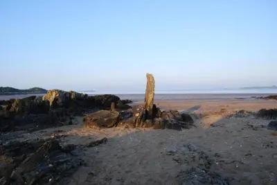 a tree stump sitting on a beach near the water at The Shack, Cally Avenue, Gatehouse of Fleet, Dumfries and Galloway, DG7 2 DH in Gatehouse of Fleet