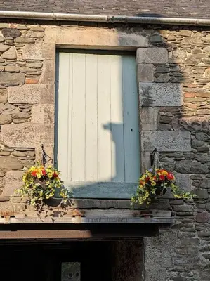 a window with two potted flowers on a stone building at Luxurious Georgian Town House in Langholm