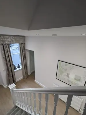 a living room with a staircase and a large screen television at Luxurious Georgian Town House in Langholm