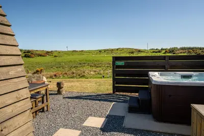 a hot tub sitting next to a wooden fence at Wigtown by Wigwam Holidays in Newton Stewart