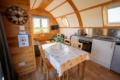 a kitchen with a table with chairs and a clock at Wigtown by Wigwam Holidays in Newton Stewart