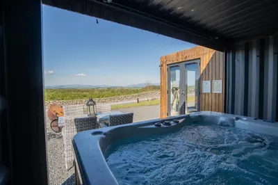 a hot tub in a room with a large window at Wigtown by Wigwam Holidays in Newton Stewart