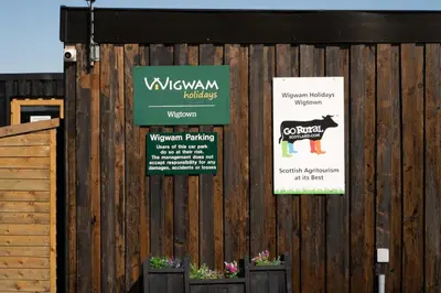 a wooden fence with signs on it with plants at Wigtown by Wigwam Holidays in Newton Stewart