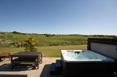 a hot tub on a patio with a picnic table at Wigtown by Wigwam Holidays in Newton Stewart