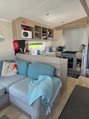 a living room with a couch and a kitchen at Barbara's Caravan Craig Tara in Ayr