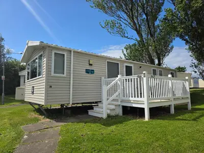 a mobile home with a porch and a white rail at Barbara's Caravan Craig Tara in Ayr