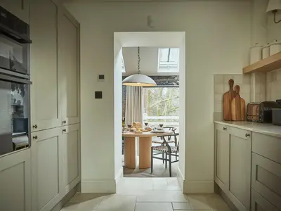 a kitchen with white cabinets and a dining room at Eskdale Retreat in Holmrook