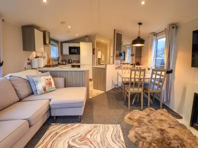 a living room with a couch and a kitchen at Highlands Way Lodge in Workington