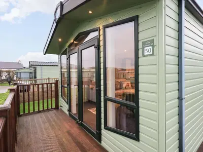 a green house with sliding glass doors on a deck at Highlands Way Lodge in Workington