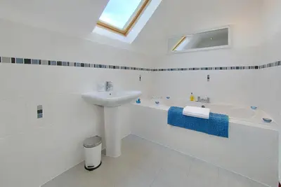 a white bathroom with a sink and a bath tub at Inchlonaig House in Port William