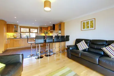 a living room with a leather couch and a kitchen at Inchlonaig House in Port William