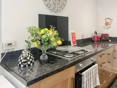 a kitchen counter with a vase of oranges and flowers at Beachcomber Apartment in Girvan