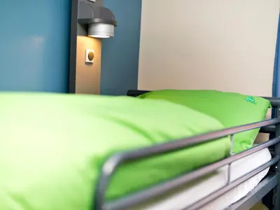 a hospital bed with a green pillow on it at YHA Wasdale Hall in Nether Wasdale