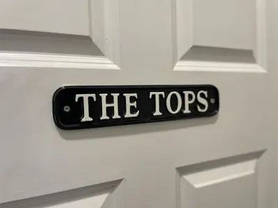 a sign that says the tops on a white door at The Tops in Keswick