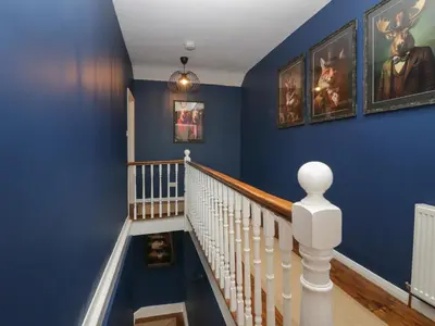 a staircase with blue walls and white railings at Benstead Cottage in Seascale