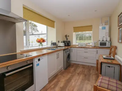 a kitchen with white cabinets and a counter top at Benstead Cottage in Seascale
