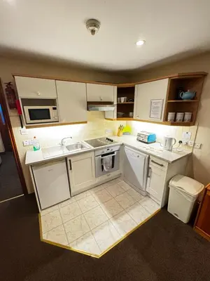 a small kitchen with white cabinets and appliances at The Wasdale Head Inn & Apartments in Seascale