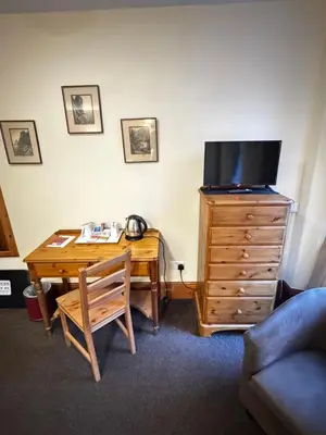 a room with a desk with a television and a wooden dresser at The Wasdale Head Inn & Apartments in Seascale