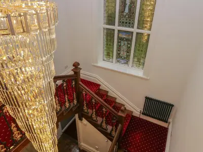 a staircase with christmas decorations and a window and a chandelier at Beechgrove Manor in Workington