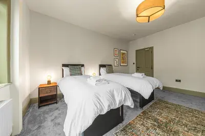 a bedroom with two beds and a table with a lamp at Boutique Home in Lake District, West Cumbria in Workington