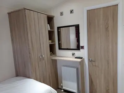 a bedroom with a bed and a cabinet with a mirror at Muirfield cosy retreat in Girvan