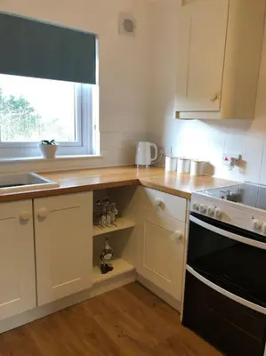 a kitchen with white cabinets and a black stove top oven at Station House Flat on outskirts of Thornhill in Thornhill
