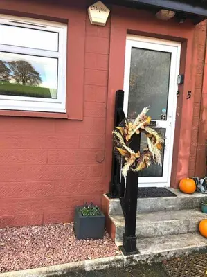 a front door of a house with a scarecrow next to it at Station House Flat on outskirts of Thornhill in Thornhill