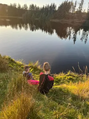 two children sitting on the grass near a lake at Station House Flat on outskirts of Thornhill in Thornhill