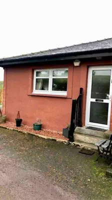a red house with two windows and a porch at Station House Flat on outskirts of Thornhill in Thornhill