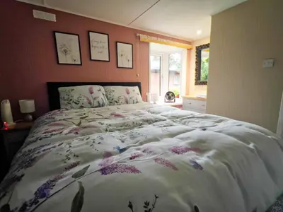 a bedroom with a large bed with flowers on it at Lodge by the Lake - Lake District - Hot Tub in Bassenthwaite