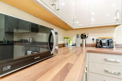 a kitchen with a microwave and a wooden floor at John Dalton House in Cockermouth