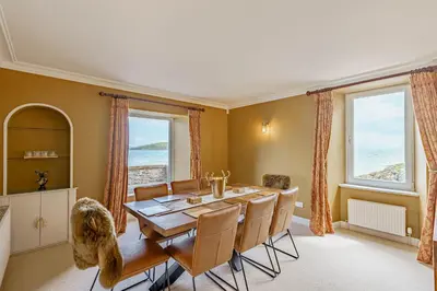a dining room with a table and chairs and windows at Balcary Tower in Castle Douglas