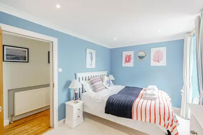 a bedroom with blue walls and a bed with striped sheets at Balcary Tower in Castle Douglas