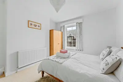 a white bedroom with a bed and a window at The Escape in Portinscale